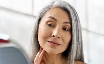 Dentures patient in San Antonio looking at their face in the mirror