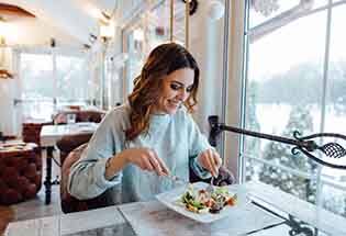 Woman smiling while eating healthy meal at restaurant