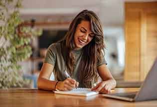 Woman smiling while taking notes on notepad